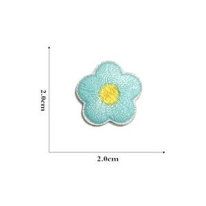Close-up of blue floral embroidery patch with yellow center, 2cm size measurement