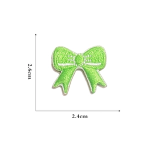 Macro detail of a 2.6cm mini green embroidered bow patch for DIY crafts and doll clothing
