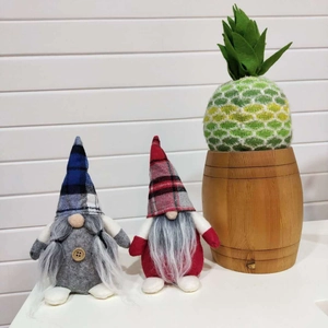 Close-up of Nordic Christmas gnomes with plaid hats and a knitted pineapple in a barrel