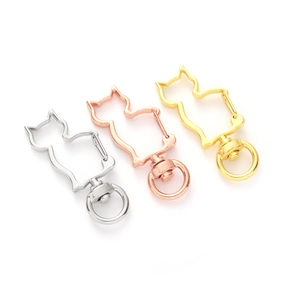 Three cat-shaped metal keychains in silver, rose gold and gold finishes on white background