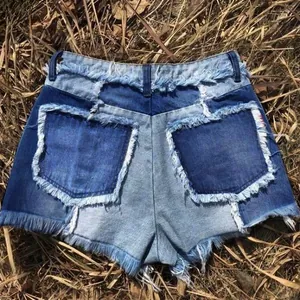 Vue détaillée à plat d'un short en jean patchwork avec bords effilochés sur l'herbe