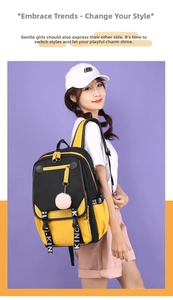 Detail eines gelb-schwarzen Canvas-Rucksacks mit bedruckten Trägern und rosa Plüsch-Anhänger