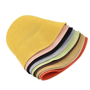 Stack of colorful knitted bucket hats in yellow, pink, and black on white background