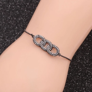 Macro detail of triple interlocking pave infinity rings on a black slider bracelet