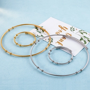 Minimalist gold and silver twisted wire jewelry set with bead accents on blue background