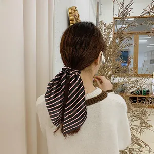 Detail of red and white striped satin hair scarf tied on a low ponytail