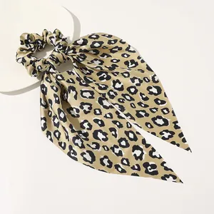 Detailed macro shot of satin leopard print hair scrunchie with long ribbons on a white tray