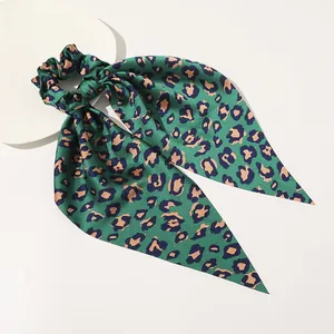 Detail of satin leopard print hair scrunchie with long ribbons in emerald green