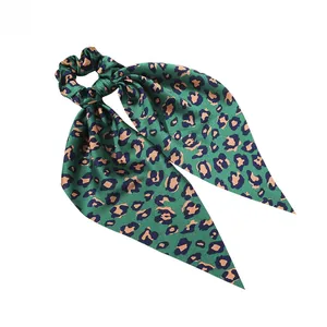 Detail of green leopard print satin scrunchie with long ribbon tails and silky texture