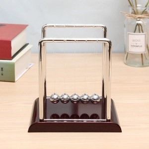 Detailed view of Newton's Cradle with polished metal balls on a mahogany wood base