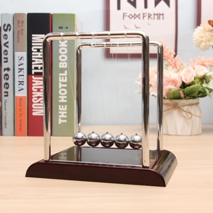 Close-up of metal Newton's Cradle with a wooden base on a modern office desk setup