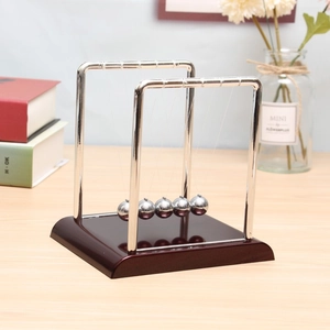 Detailed close-up of metal Newton's cradle balls on a dark brown wooden base for desk decor