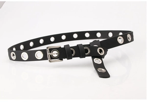 Détail d'une ceinture en cuir PU noir avec œillets métalliques argentés et boucle carrée