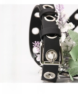 Détail de la ceinture en cuir noir avec boucle en alliage argenté et œillets métalliques
