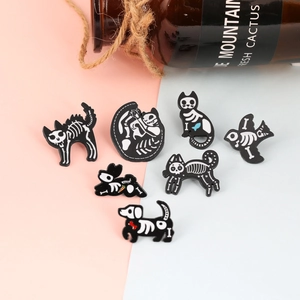 Detailed flat lay of black enamel animal skeleton brooches on a pink and blue background