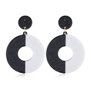 Macro detail of geometric black and white acrylic drop earrings with gold-tone hardware