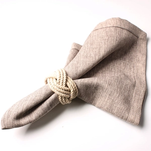Detail of a natural jute woven napkin ring on a beige linen fabric with rustic texture