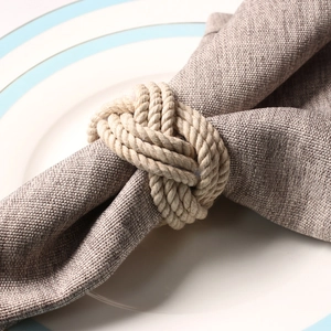Close-up of beige woven jute rope napkin ring knot on a grey linen napkin