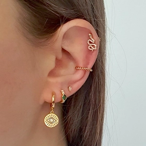 Golden snake-shaped earring set with crystals and evil eye pendant on model ear