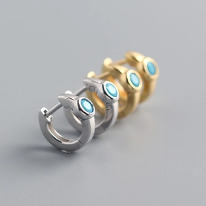 Detail of silver and gold huggie earrings with round blue turquoise stone inlays
