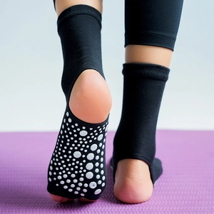 Mid-calf black non-slip yoga socks with open-heel design on a professional yoga mat