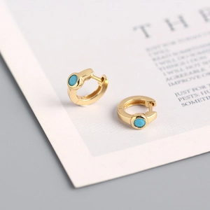 Macro detail of gold S925 silver huggie earrings featuring turquoise blue zircon stones