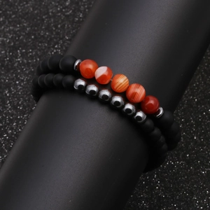 Matte black and orange agate beaded bracelet set on a professional display stand