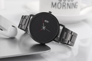Macro shot of black quartz watch face featuring red hands and calendar window on laptop