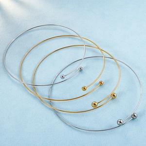Minimalistische Edelstahlarmbänder mit Gold- und Silberperlen auf blauem Hintergrund