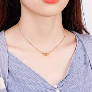 Minimalistische goldene Halskette mit Kronenanhänger an einer Frau im Close-up