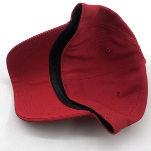 Close-up of red baseball cap showing mesh fabric, brim stitching, and black inner sweatband
