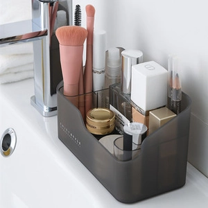 Translucent smoky gray plastic organizer with sections for makeup and skincare products