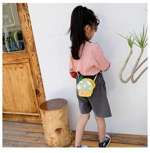 Detail of yellow mushroom crossbody bag with green leaf accent on a child model