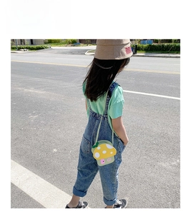 Detail of mushroom crossbody bag paired with mint tee and denim overalls on child