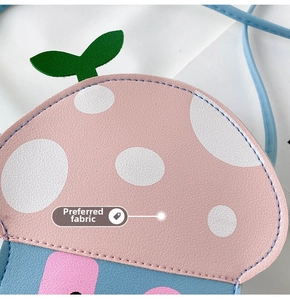 Close-up of pink mushroom cartoon bag with white dots and blue textured leather surface