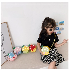 Child wearing a cute mushroom-shaped crossbody bag in a bright lifestyle setting