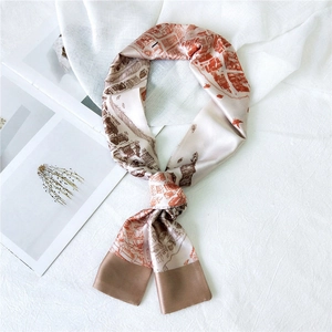 Detail showing the architectural print and silk texture of this brown narrow neck scarf