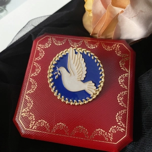 Vintage enamel peace dove brooch with gold floral border on elegant jewelry box