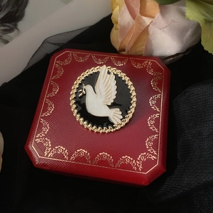 Detail of a vintage peace dove brooch on a gold-patterned red jewelry box