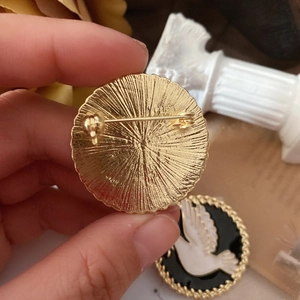 Detail of vintage enamel peace dove brooch showing golden pin back and radial texture