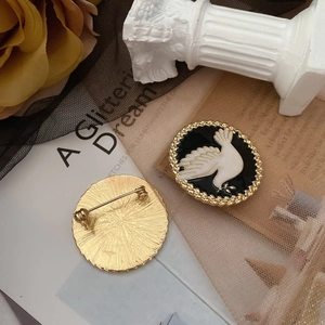 Detail of vintage pigeon enamel brooch featuring gold metal back and safety pin clasp