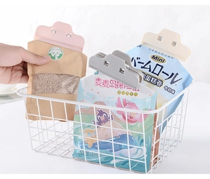 Pink plastic food bag sealer clip used on snack packaging in a kitchen storage basket
