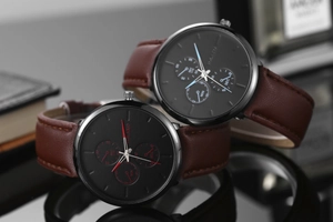 Vue détaillée des cadrans noirs avec accents rouges et bleus sur montres en cuir brun