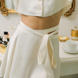 Détail d'un ensemble en satin blanc avec haut court et mini-jupe à lacets taille haute