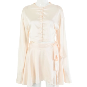 Détail de l'ensemble deux pièces en satin rose clair avec haut boutonné et jupe nouée