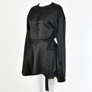 Détail d'un ensemble deux pièces noir en soie avec cardigan long et jupe à nouer