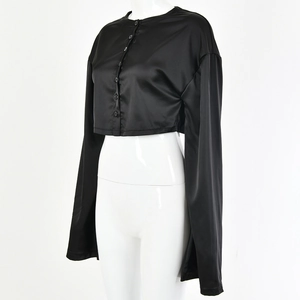 Détail du crop top noir brillant en satin à manches longues avec boutons sur un mannequin