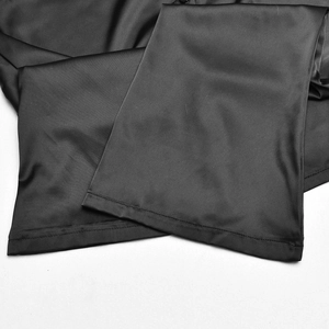 Gros plan sur un tissu en satin noir montrant la texture lisse et les détails de couture