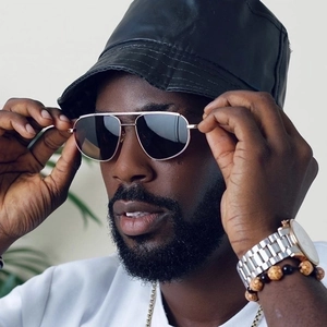 Golden pilot sunglasses and black leather bucket hat set worn by a fashion male model