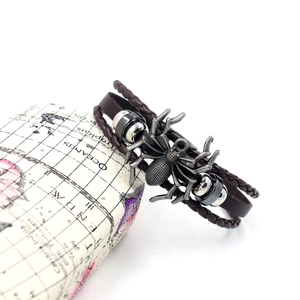 Detail view of a vintage brown layered leather bracelet with a silver spider charm and beads
